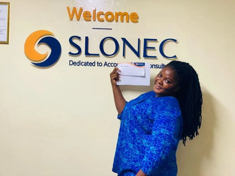 A SLONEC team member at the Welcome sign in the SLONEC office, Freetown