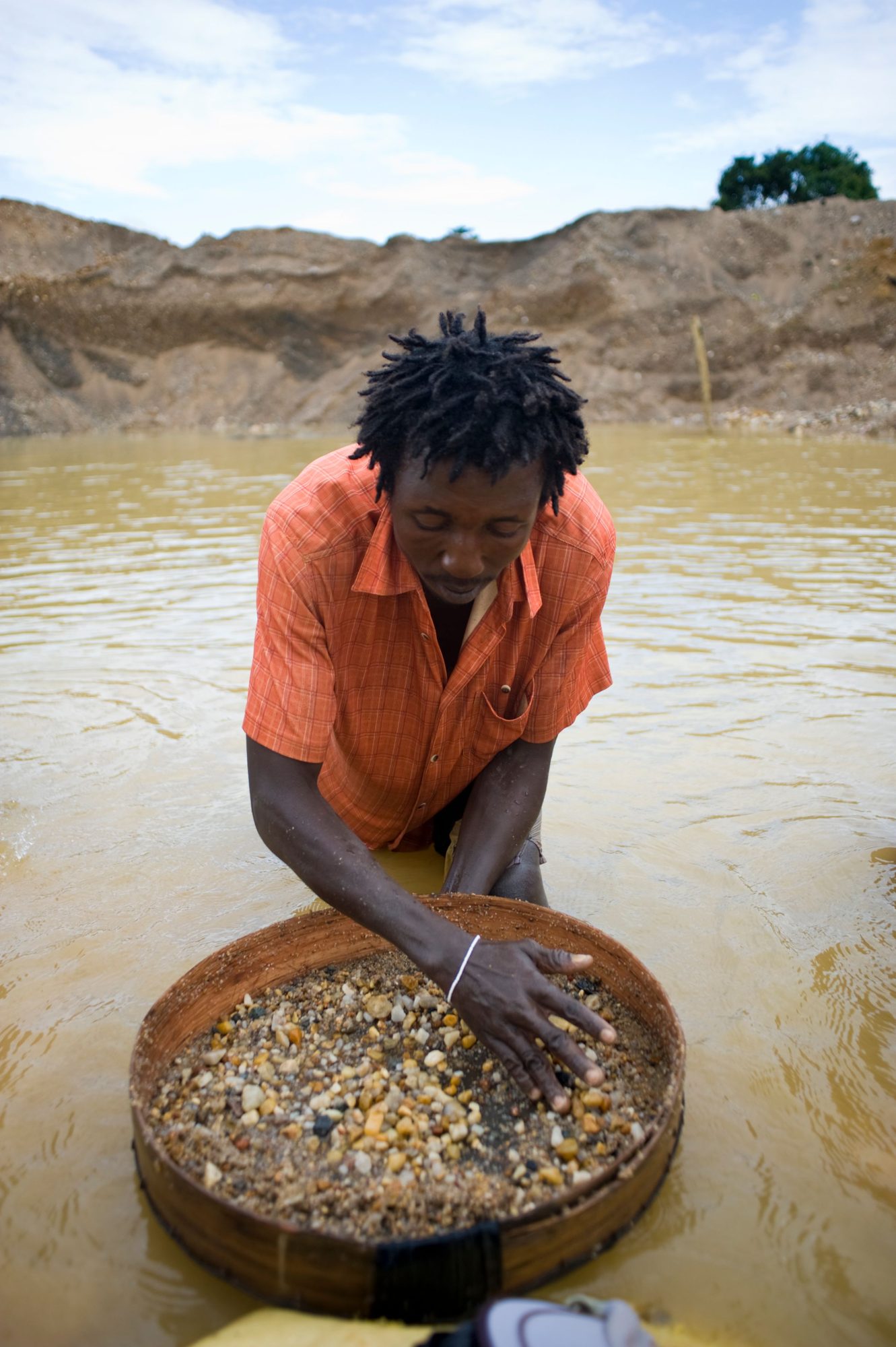 A miner processing gravel in a water-filled pit in Eastern Province, Sierra Leone